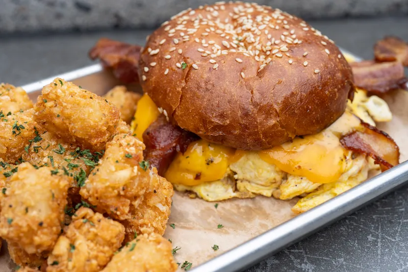 Breakfast sandwich with bacon, egg and cheese and tater tots at Park 101 Carlsbad brunch