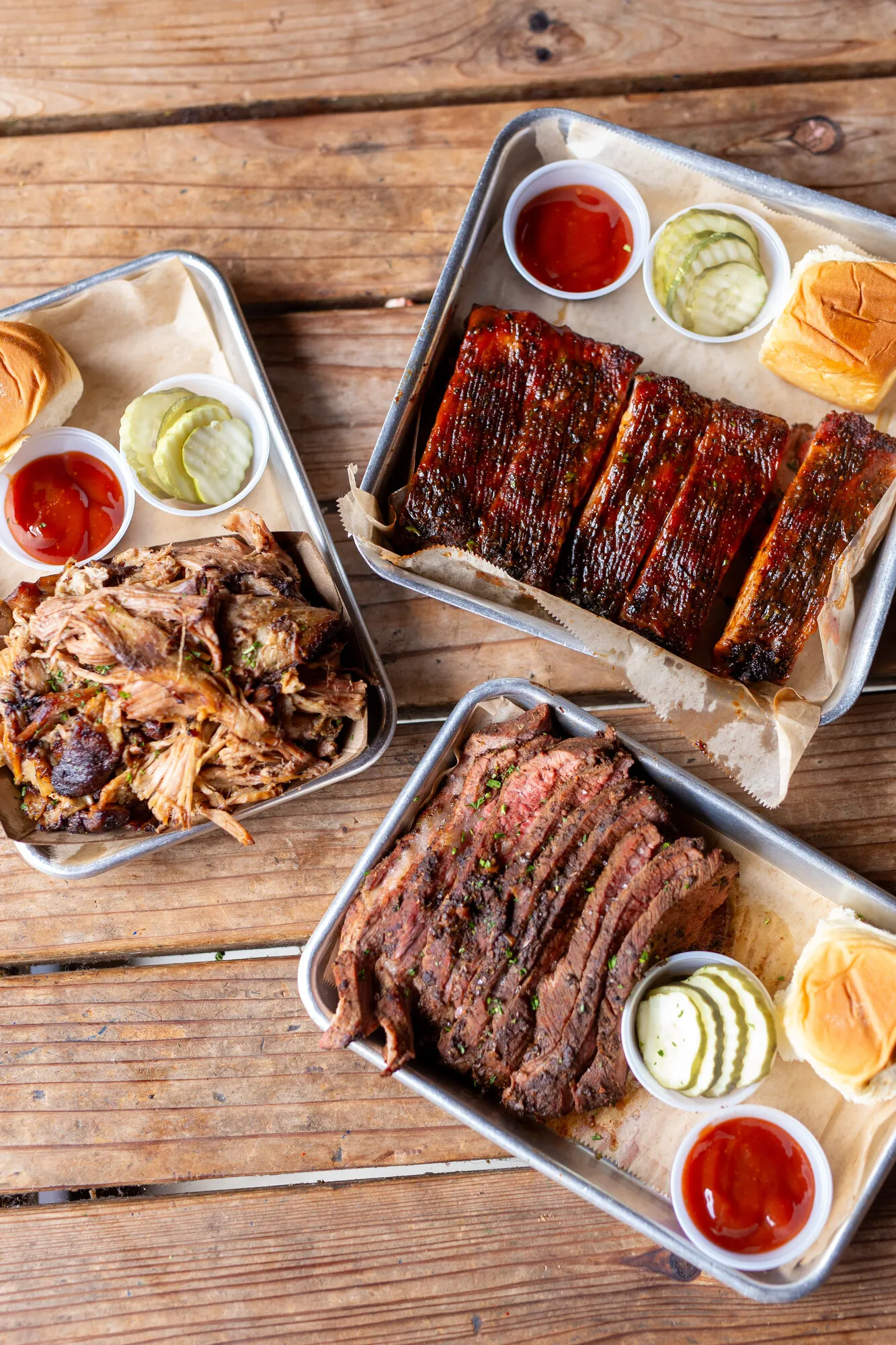Three BBQ platters of pulled pork, St. Louis ribs, and sliced brisket from the Park 101 smokehouse