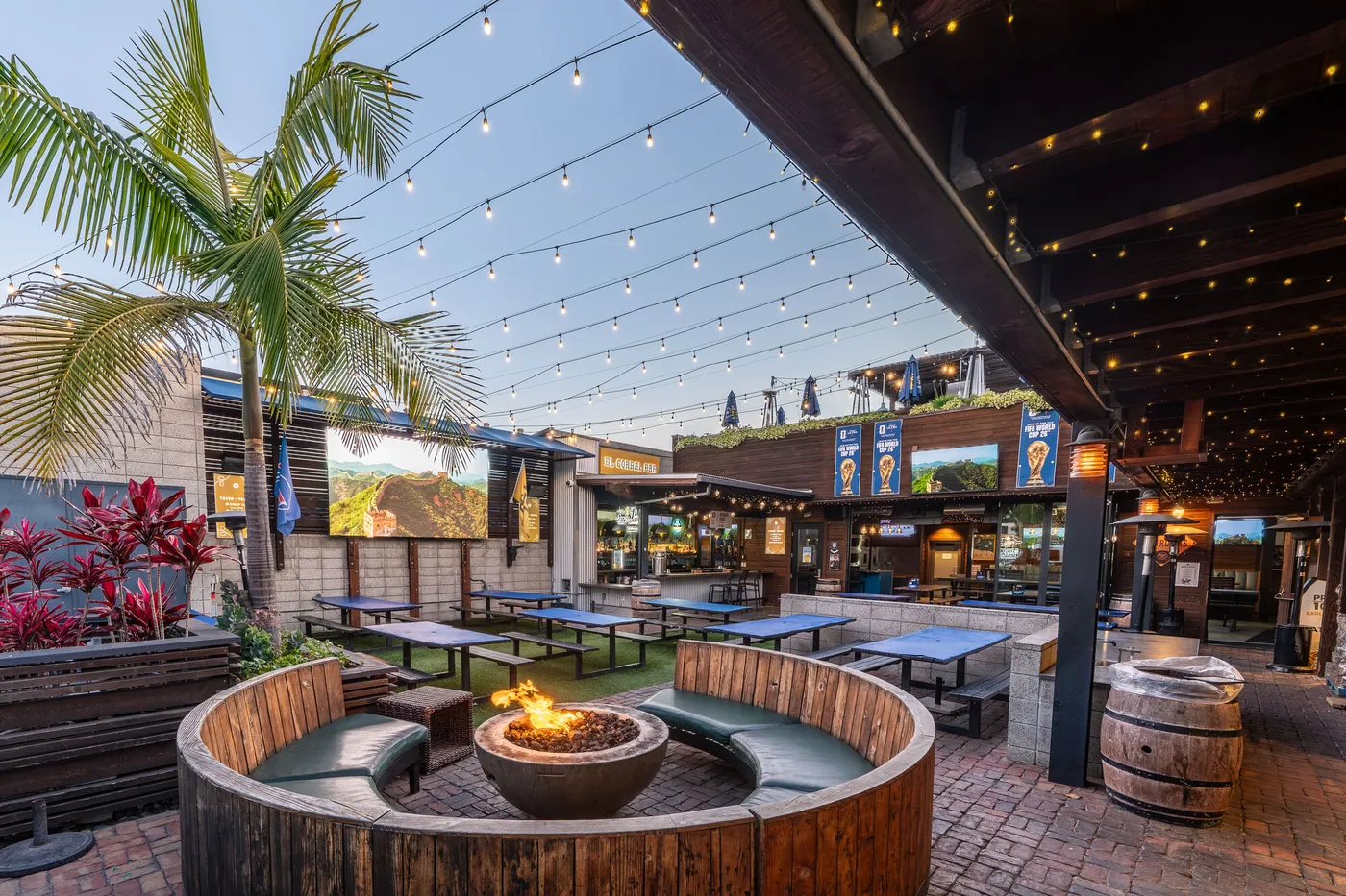 Park 101 full outdoor courtyard at dusk with fire pit seating, LED screen, tables, and multi-level venue