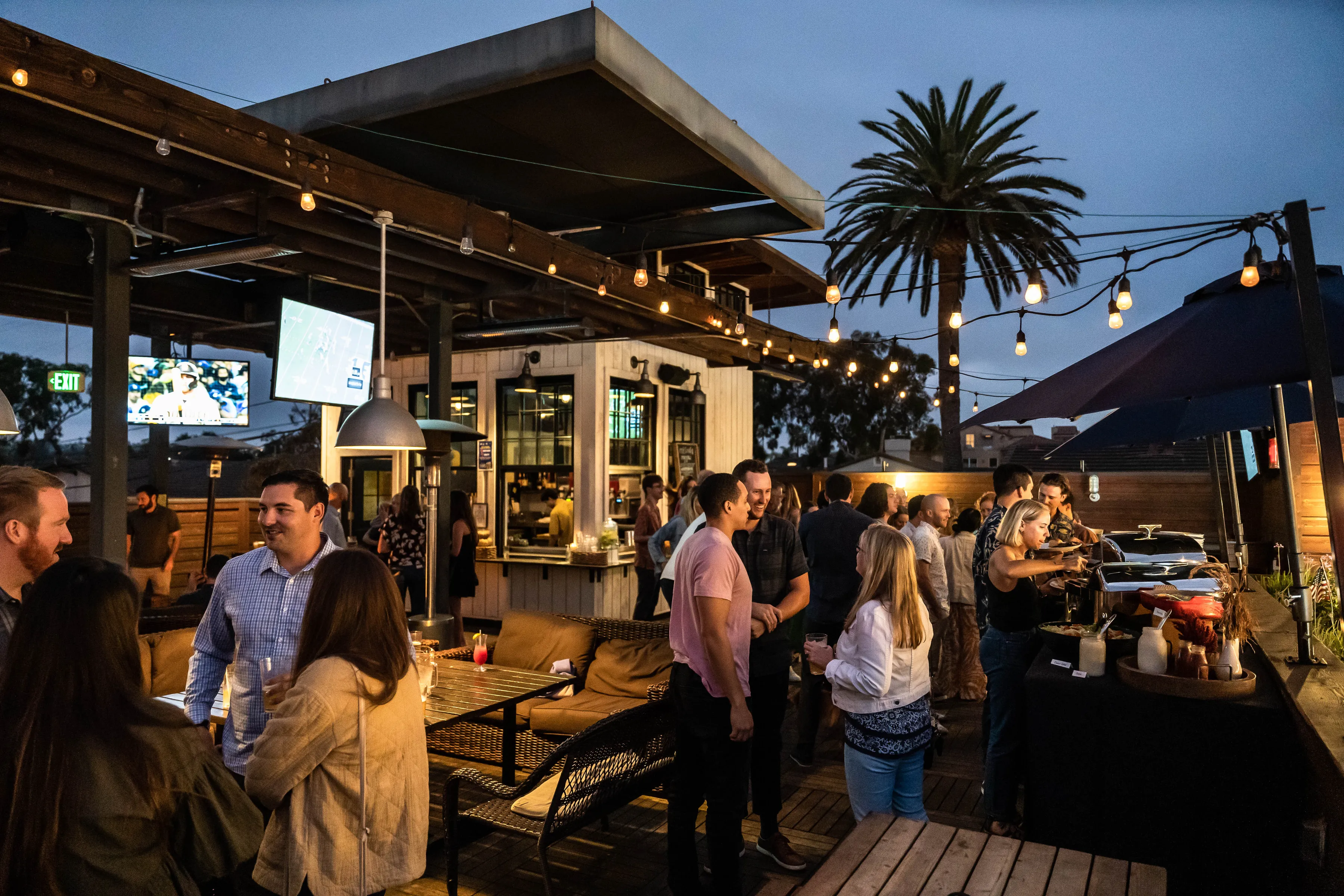 Evening group gathering on the rooftop at Park 101 Carlsbad with string lights and open-air venue