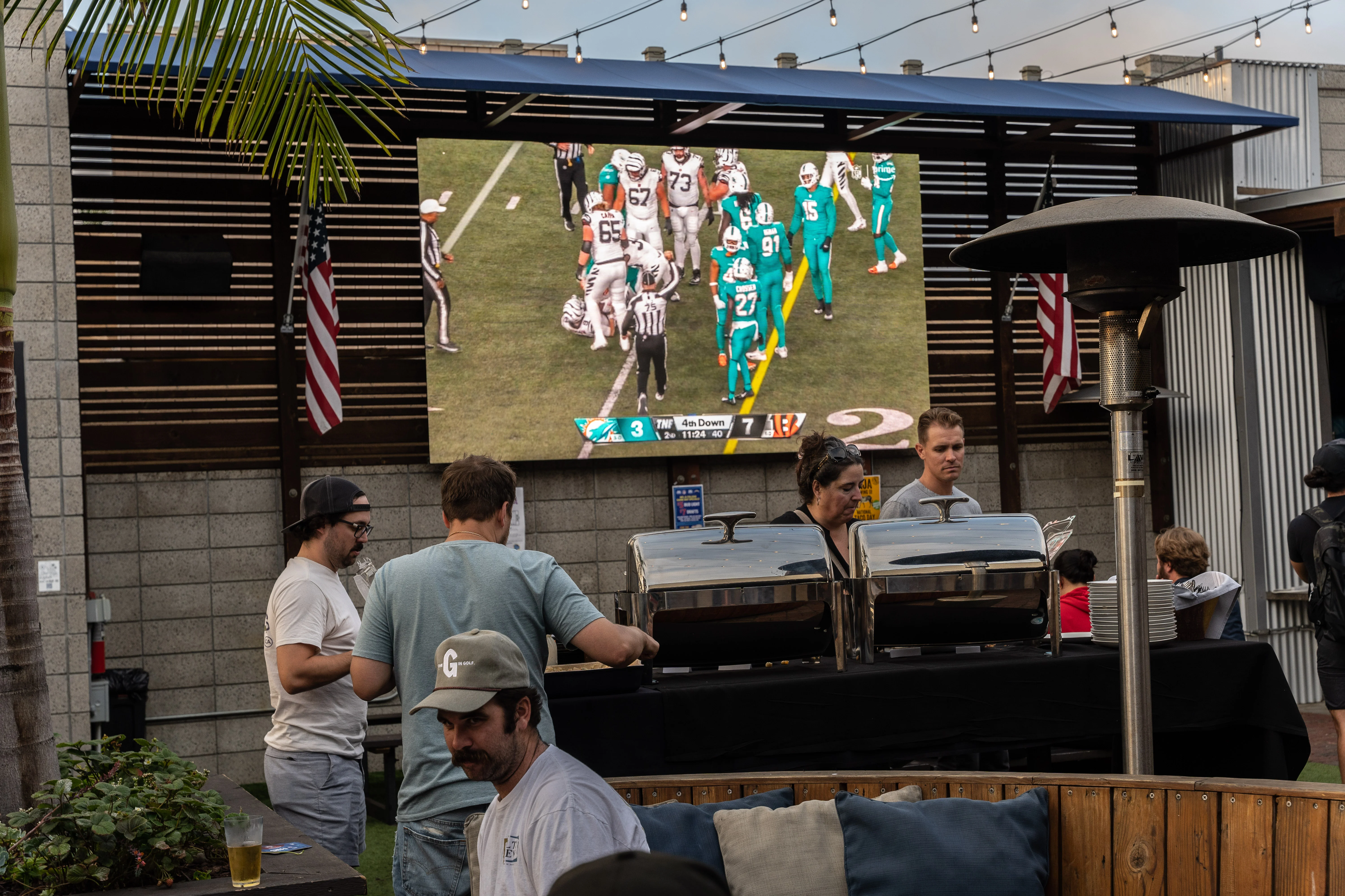 Fans watching an NFL game on the outdoor LED screen at Park 101 Carlsbad with game day food service